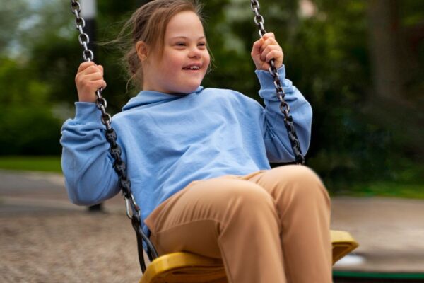 Menina com síndrome de Down se divertindo em um balanço em um parque, sorrindo