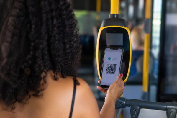 Mulher utilizando PIX em um ônibus para pagamento.