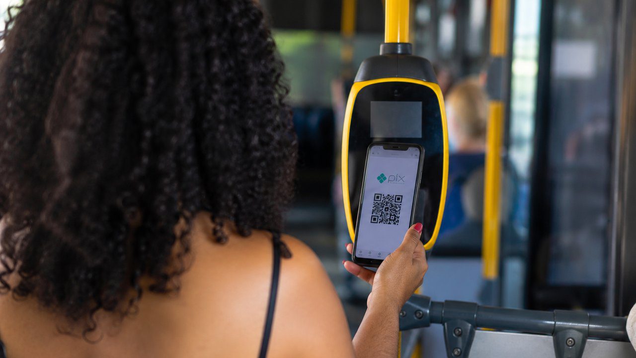 Mulher utilizando PIX em um ônibus para pagamento.