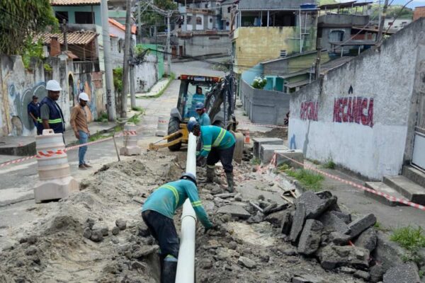 Obras em rua com encanadores instalando tubulação.