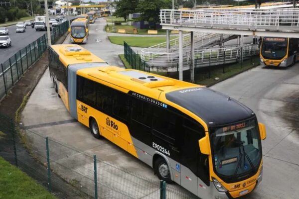 Ônibus BRT amarelo e preto na estação, transportando passageiros na Baixada Fluminense.