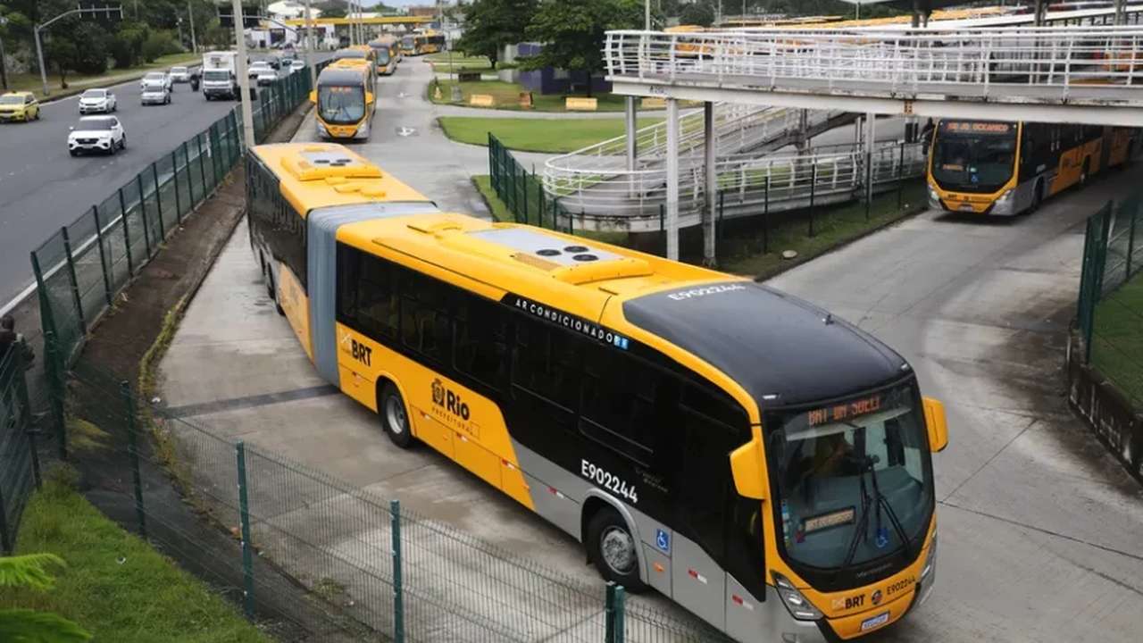 Ônibus BRT amarelo e preto na estação, transportando passageiros na Baixada Fluminense.