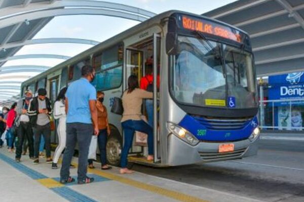 Ônibus com pessoas embarcando, refletindo debate sobre vale-transporte e custo de vida.