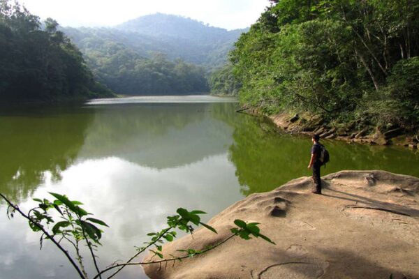 Paisagem natural com lago e pessoa observando, parte da rota turística no Rio de Janeiro.