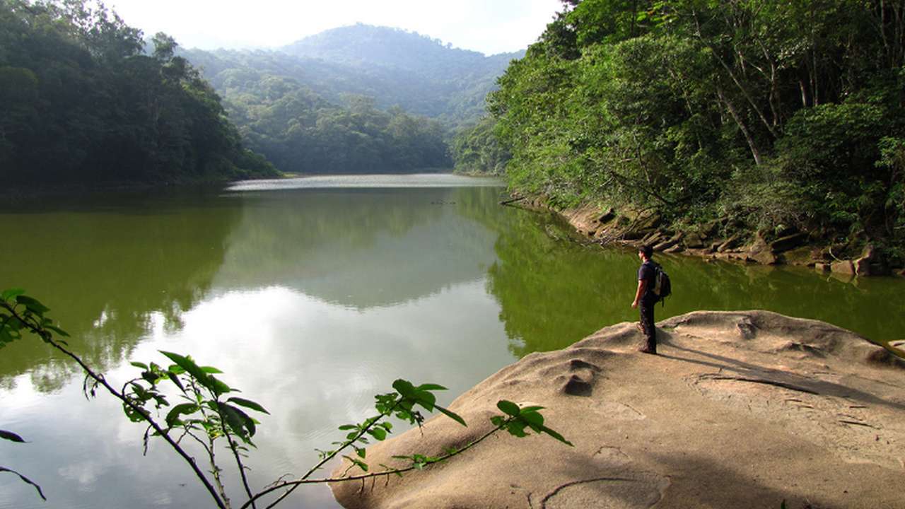 Paisagem natural com lago e pessoa observando, parte da rota turística no Rio de Janeiro.