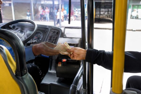 Passageiro pagando a passagem em dinheiro para o motorista de ônibus