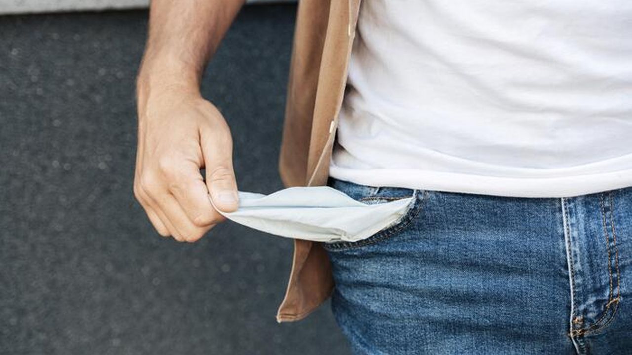 Pessoa mostra bolso vazio, simbolizando dificuldades financeiras.