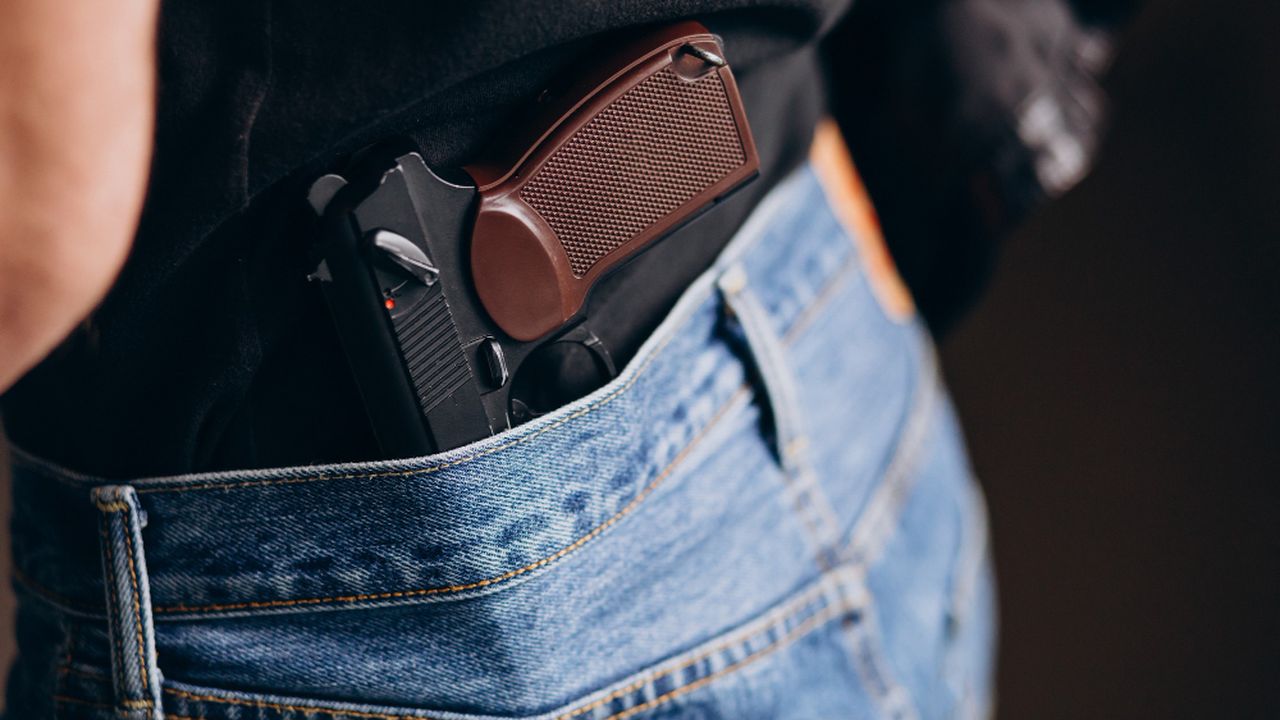 Pistola na cintura sob calça jeans