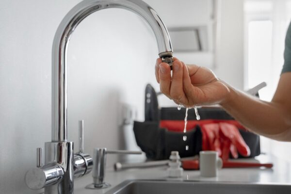 Plumber testing a faucet for leaks, water dripping from the fixture.