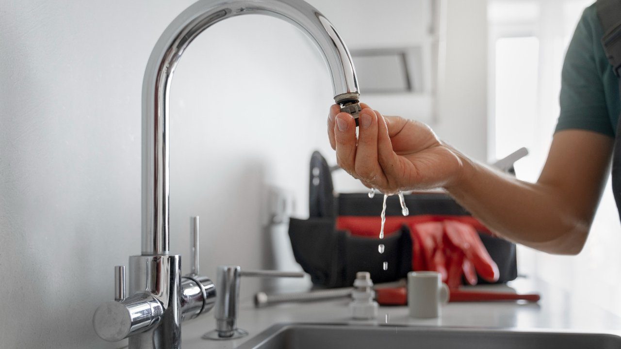 Plumber testing a faucet for leaks, water dripping from the fixture.