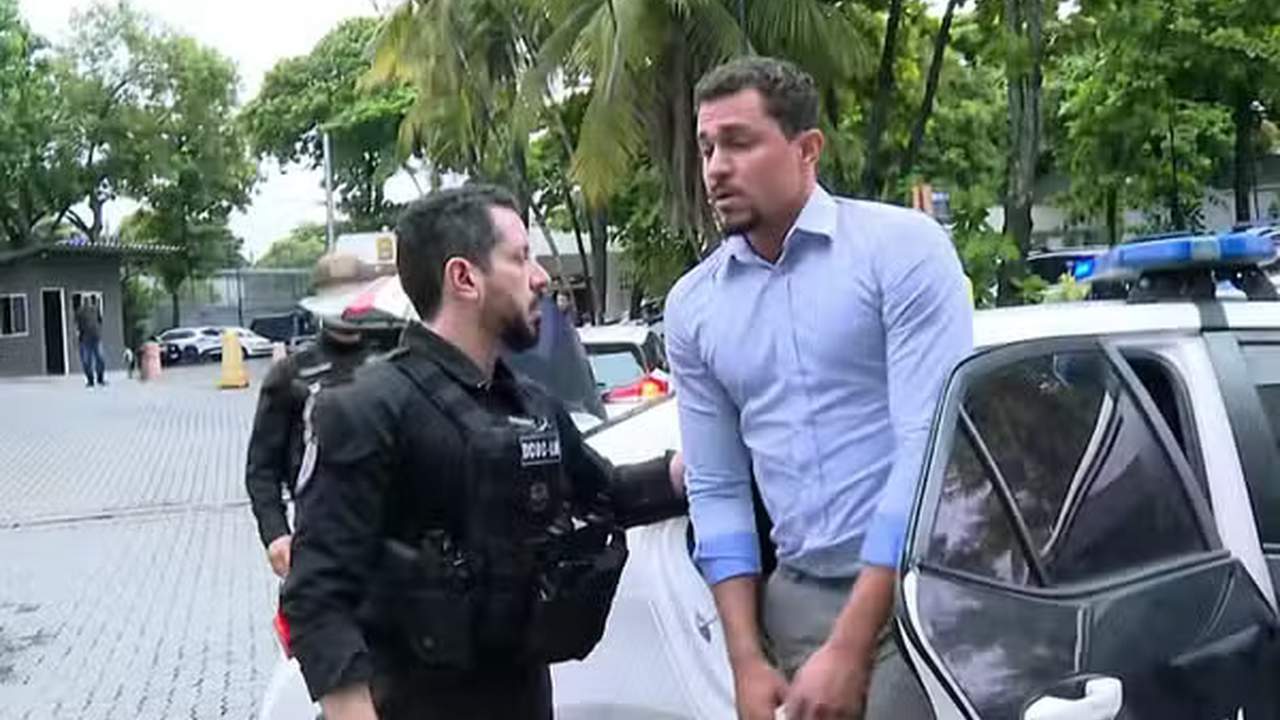 Policial conduz homem para viatura policial em investigação.