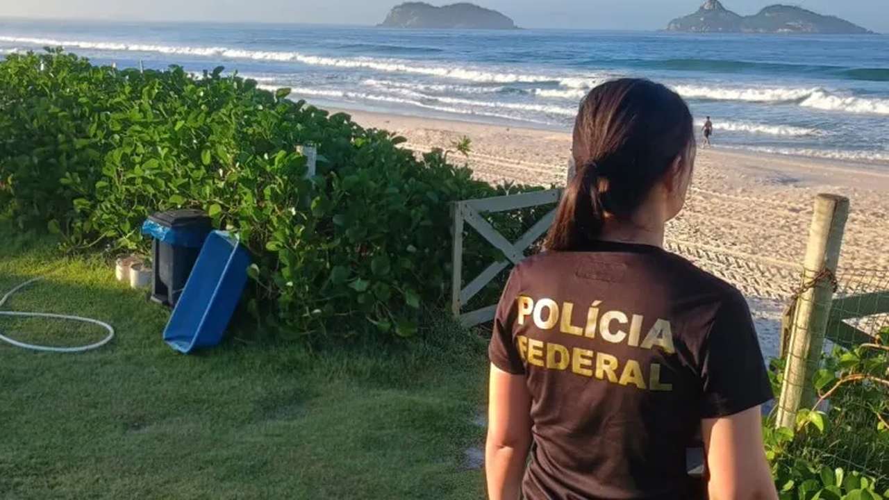 Policial Federal na praia observa área com suspeita de ocupação irregular.