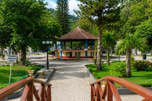 Praça arborizada em Trajano de Moraes, RJ, com coreto e paisagem.