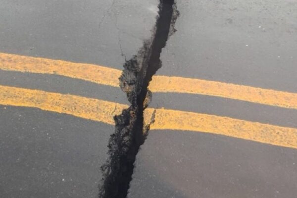 Rachadura em asfalto de viaduto com faixas amarelas