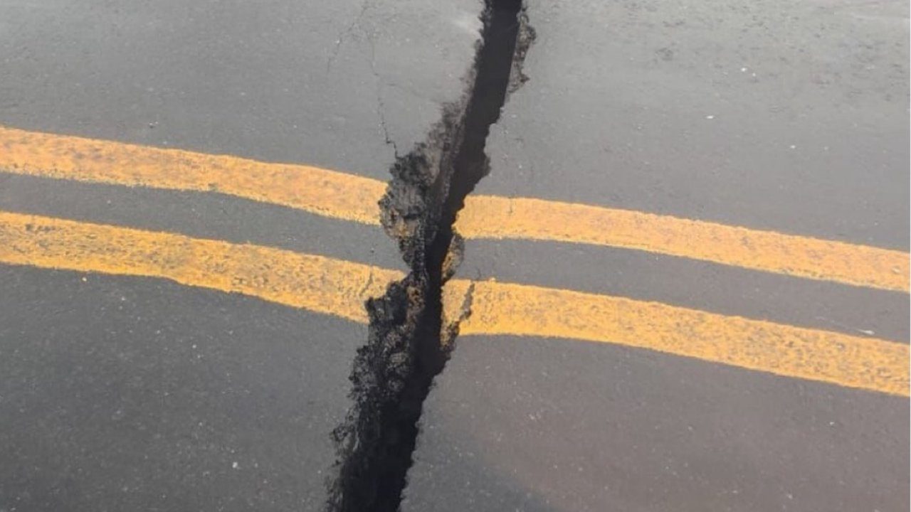 Rachadura em asfalto de viaduto com faixas amarelas