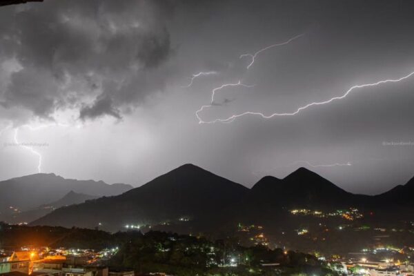 Relâmpagos iluminam o céu sobre montanhas e cidade durante tempestade em Nova Friburgo, RJ.