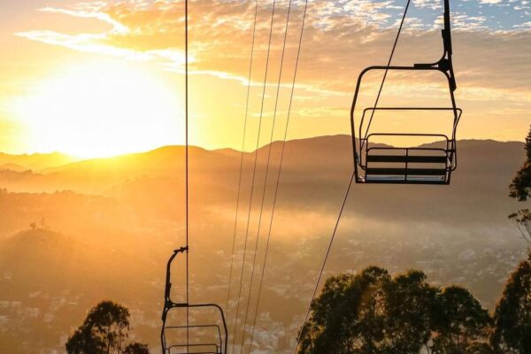Teleférico ao nascer do sol sobre montanhas e cidade, maior sistema urbano do Brasil.