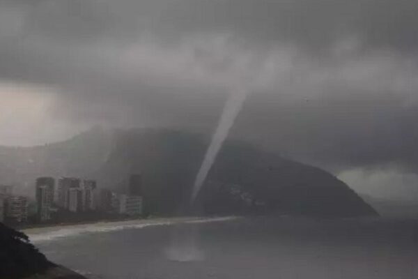 Tornado sobre a praia e cidade com tempo nublado e chuvoso