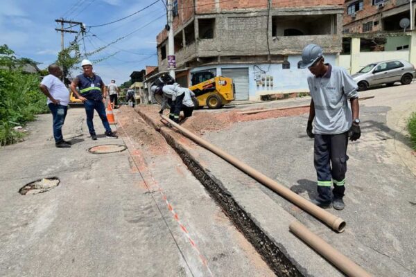 Trabalhadores instalam tubulação em rua, possivelmente relacionada a problemas de abastecimento de água.