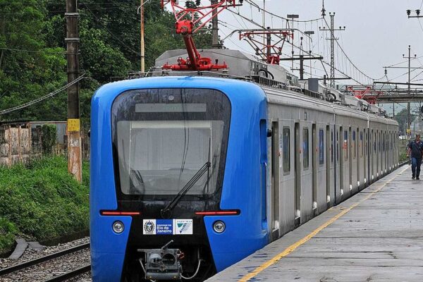 Trem azul da SuperVia em estação, com homens caminhando na plataforma e rede elétrica