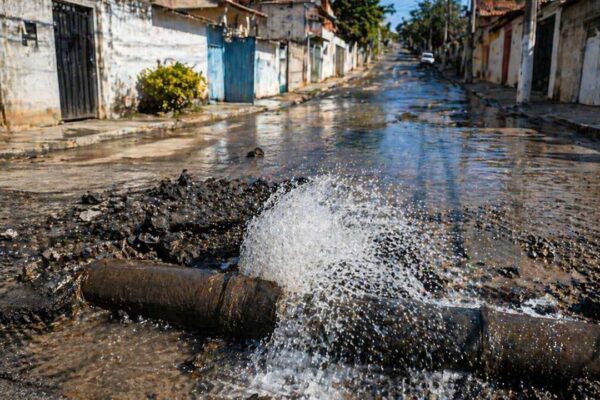 Vazamento de água em rua de cidade, mostrando impacto da falta de abastecimento.