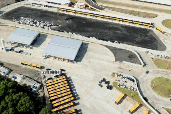 Visão aérea do novo terminal de ônibus com veículos estacionados e estruturas cobertas.