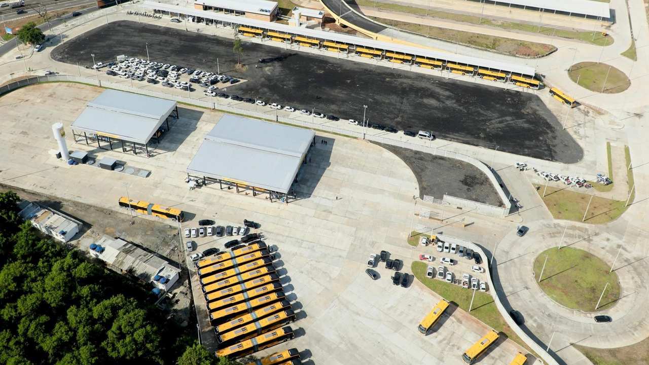 Visão aérea do novo terminal de ônibus com veículos estacionados e estruturas cobertas.