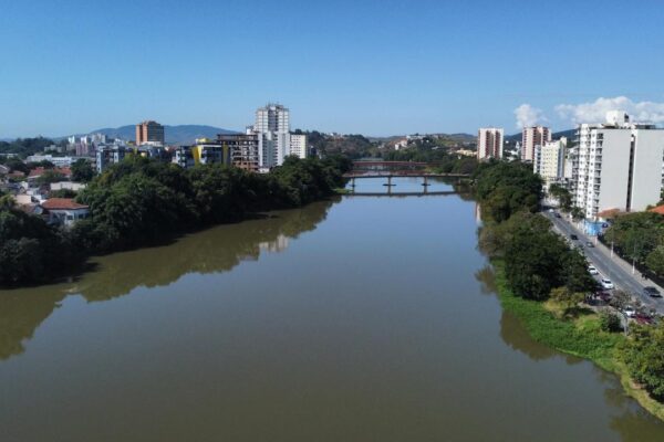 Vista panorâmica de Resende, cidade fluminense, com rio, prédios e céu azul.