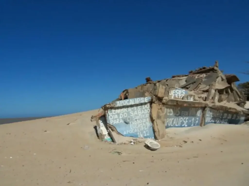 Escombros de construção parcialmente cobertos pela areia em Atafona
