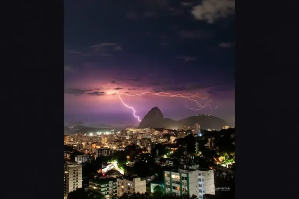 Relâmpago ramificado ilumina o céu sobre o Pão de Açúcar e os prédios do Rio de Janeiro à noite.