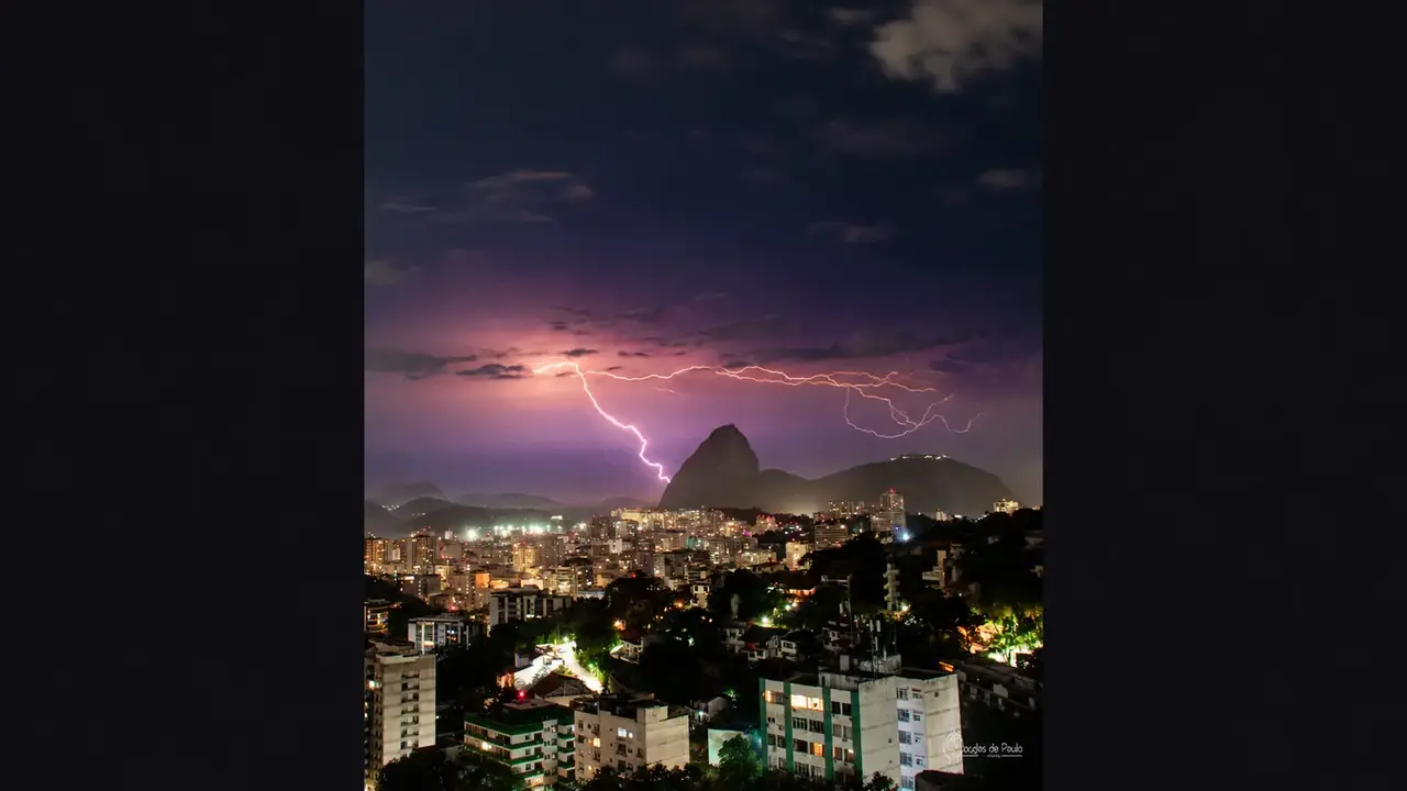 Relâmpago ramificado ilumina o céu sobre o Pão de Açúcar e os prédios do Rio de Janeiro à noite.
