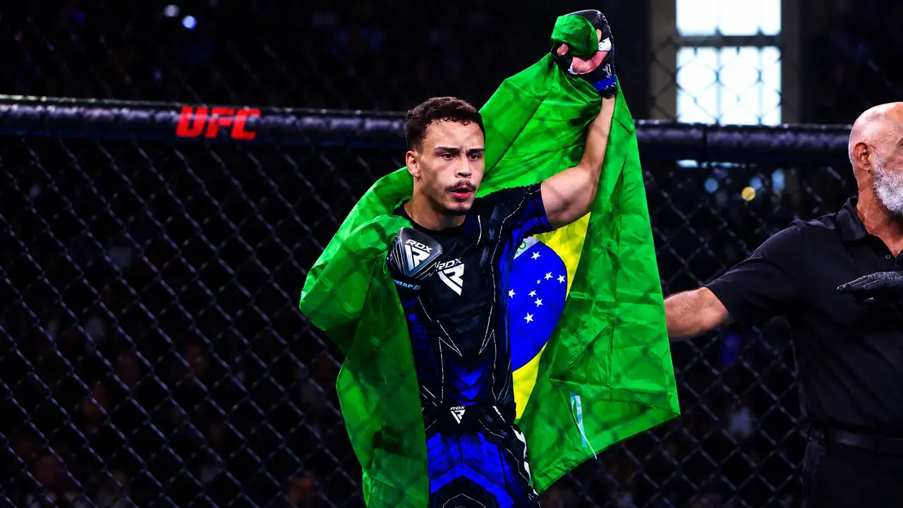 Davi Schuenck entra na arena com os braços abertos e a bandeira do Brasil nas costas.