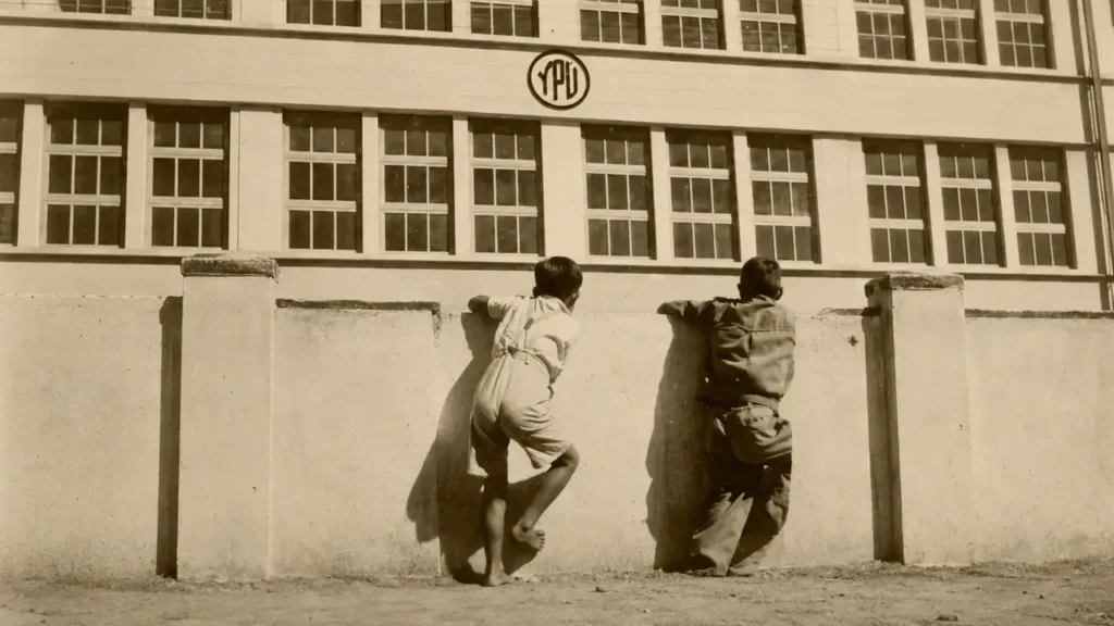 Duas crianças observam a antiga Fábrica Ypu por cima de um muro