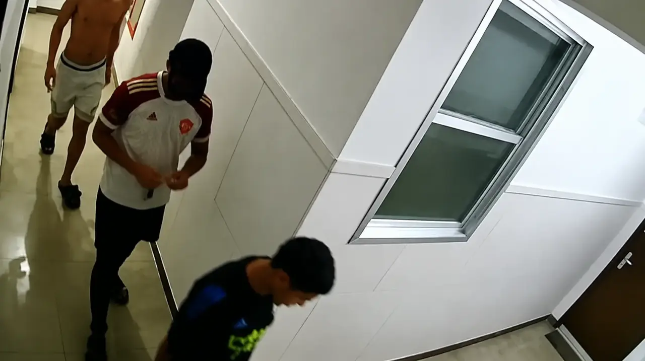 Três pessoas aparecem em um corredor, em imagem captada por câmera de segurança.