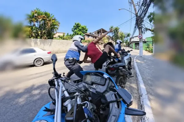 Policiais da motopatrulha abordam homem junto a motocicletas em uma rua de Niterói.