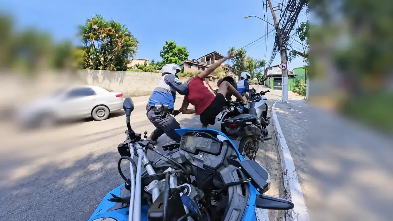 Policiais da motopatrulha abordam homem junto a motocicletas em uma rua de Niterói.