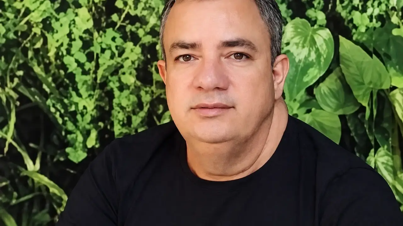 Amarildo Henrique do Nascimento veste camiseta preta diante de uma vegetação verde.