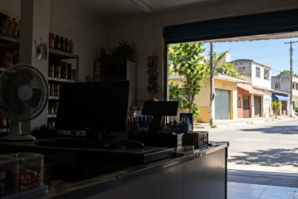 Interior de comércio com luzes apagadas e telas desligadas, enquanto a rua recebe luz do sol.