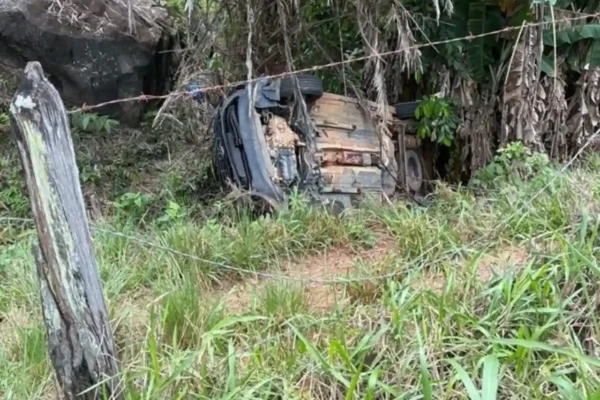 Carro capotado entre árvores e vegetação em Euclidelândia, Cantagalo.