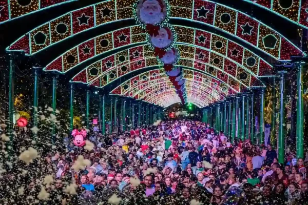 Público sob arcos de iluminação natalina com estrelas e figuras de Papai Noel em Nova Friburgo.