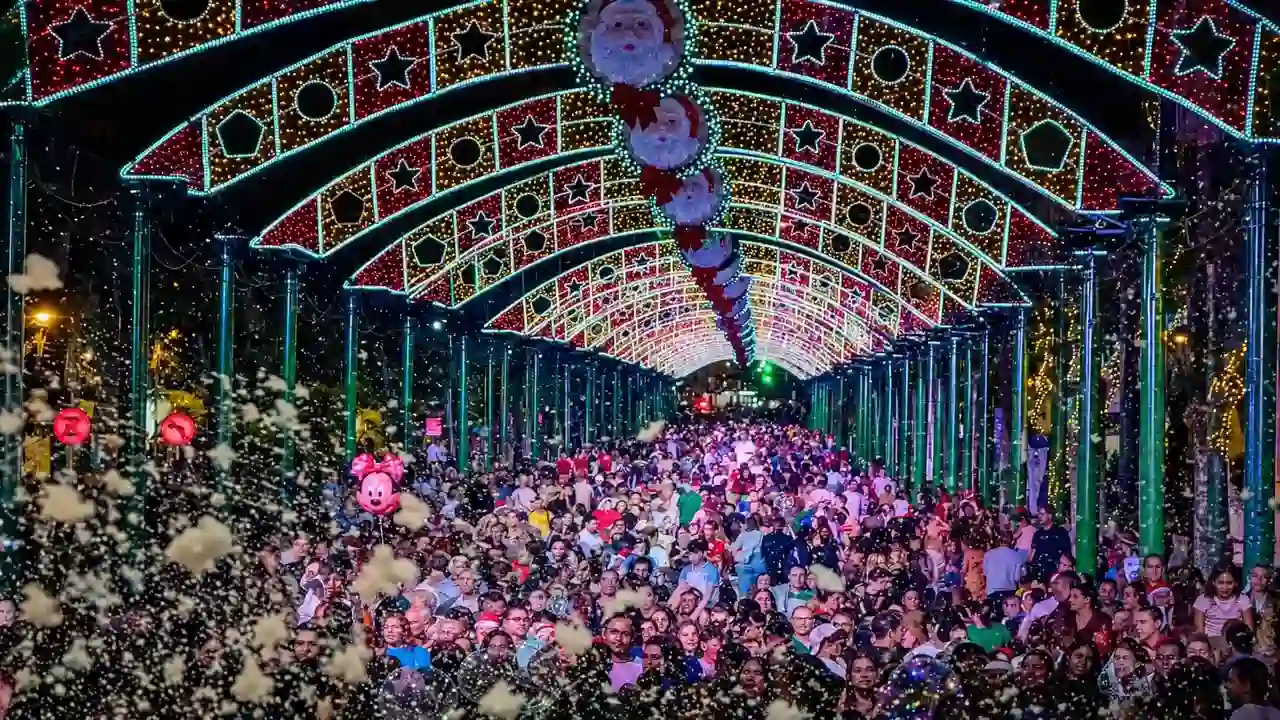 Público sob arcos de iluminação natalina com estrelas e figuras de Papai Noel em Nova Friburgo.