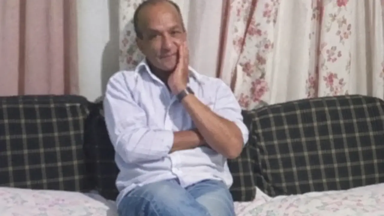 Luiz Dalter sentado em um sofá, com uma das mãos apoiada no rosto.